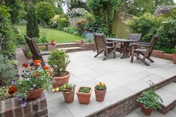 flowers in large terracotta pots in a pretty garden with autumnal trees in the background